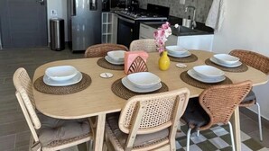 Ein Essbereich mit einem runden Tisch, sechs Stühlen und einer Küche im Hintergrund.