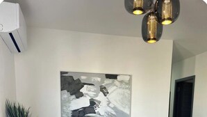 Ein Wohnzimmer mit einem dunklen Sofa, einem Couchtisch, einem Gemälde und einer Topfpflanze.