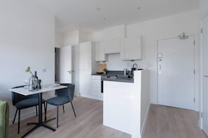 Une cuisine moderne avec des meubles blancs, un îlot central et un coin repas équipé de deux chaises.