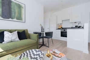 Un salon moderne comprenant un canapé, une table basse et un coin repas avec des chaises.
