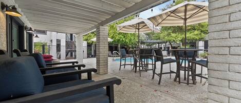 An outdoor patio with seating, umbrellas, and a pool.
