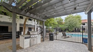 Eine Außenpatio mit Grill, Mülleimer und Poolbereich.