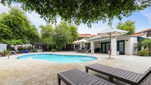 Ein Swimmingpool mit Liegestühlen, eine überdachte Terrasse und ein Gebäude mit rotem Dach.
