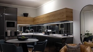 Une cuisine moderne dotée d’appareils électroménagers intégrés, un coin repas avec une table ronde et des chaises, et un grand miroir.