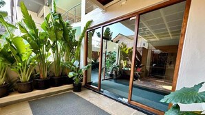 A building entrance with a glass door, potted plants, and a stone floor.