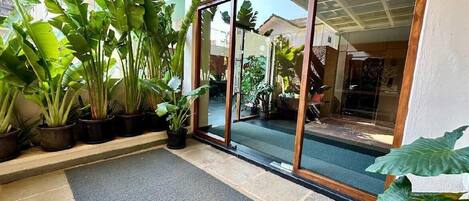 A building entrance with a glass door, potted plants, and a stone floor.