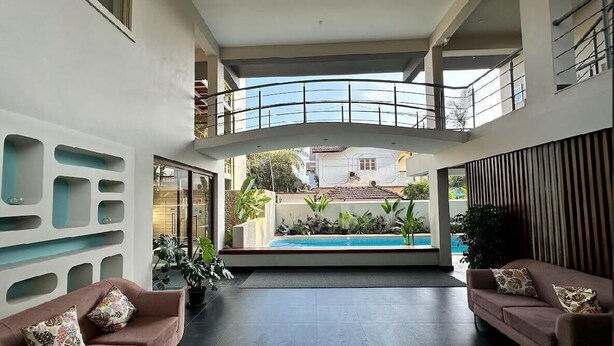 A spacious indoor area with a pool, two sofas, and a balcony.