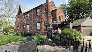A brick building with a patio area, a black metal fence, and outdoor furniture. - Central-Immaculate-Parking-Fenced Yard-Dining (Fort Wayne)