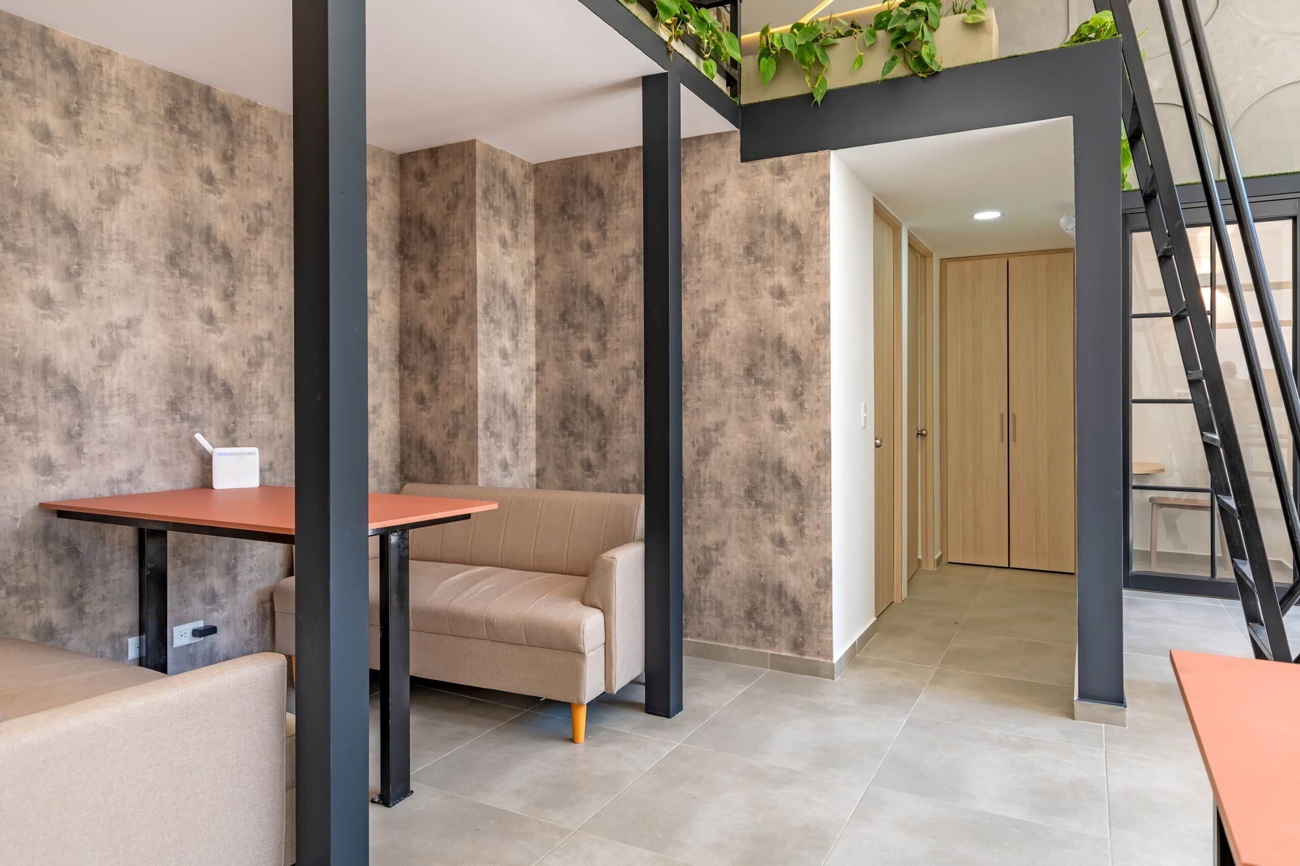 A modern interior with a sofa, a table, and a staircase with plants.