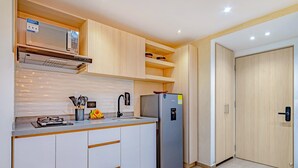 Cocina moderna con muebles blancos, un refrigerador de acero inoxidable y un microondas sobre la encimera.