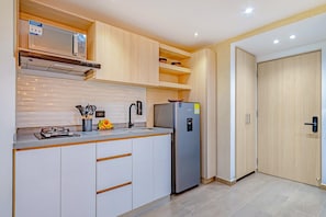 A modern kitchen with white cabinetry, a stainless steel refrigerator, and a microwave above the counter. - Edificio Habitare Cristales (Cali)