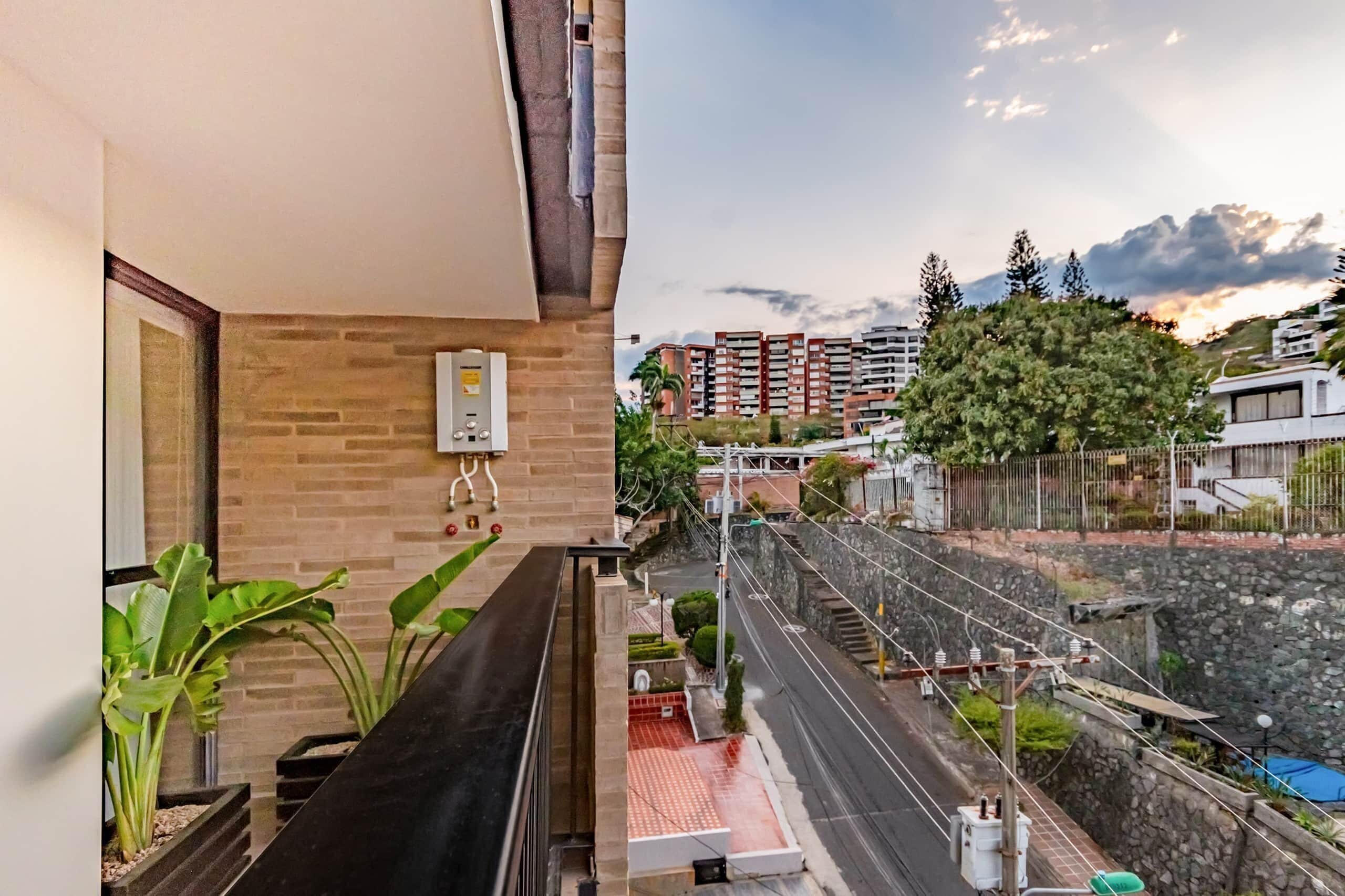 A balcony with a view of a residential area, a water feature, and a stone wall.