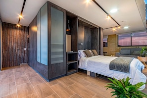 A modern bedroom with a bed, a wardrobe, and a view of the sky through a window. - Edificio Habitare Cristales (Cali)