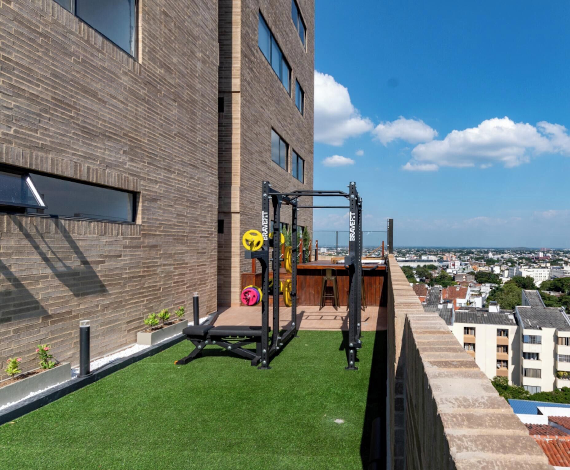 A rooftop gym with exercise equipment, a small seating area, and a view of the cityscape.