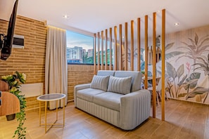 A modern living room with a sofa, a small table, and a decorative plant. - Edificio Habitare Cristales (Cali)