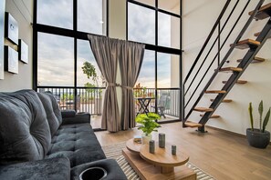 A modern living room with a sofa, a coffee table, a staircase, and a balcony with plants. - Edificio Habitare Cristales (Cali)