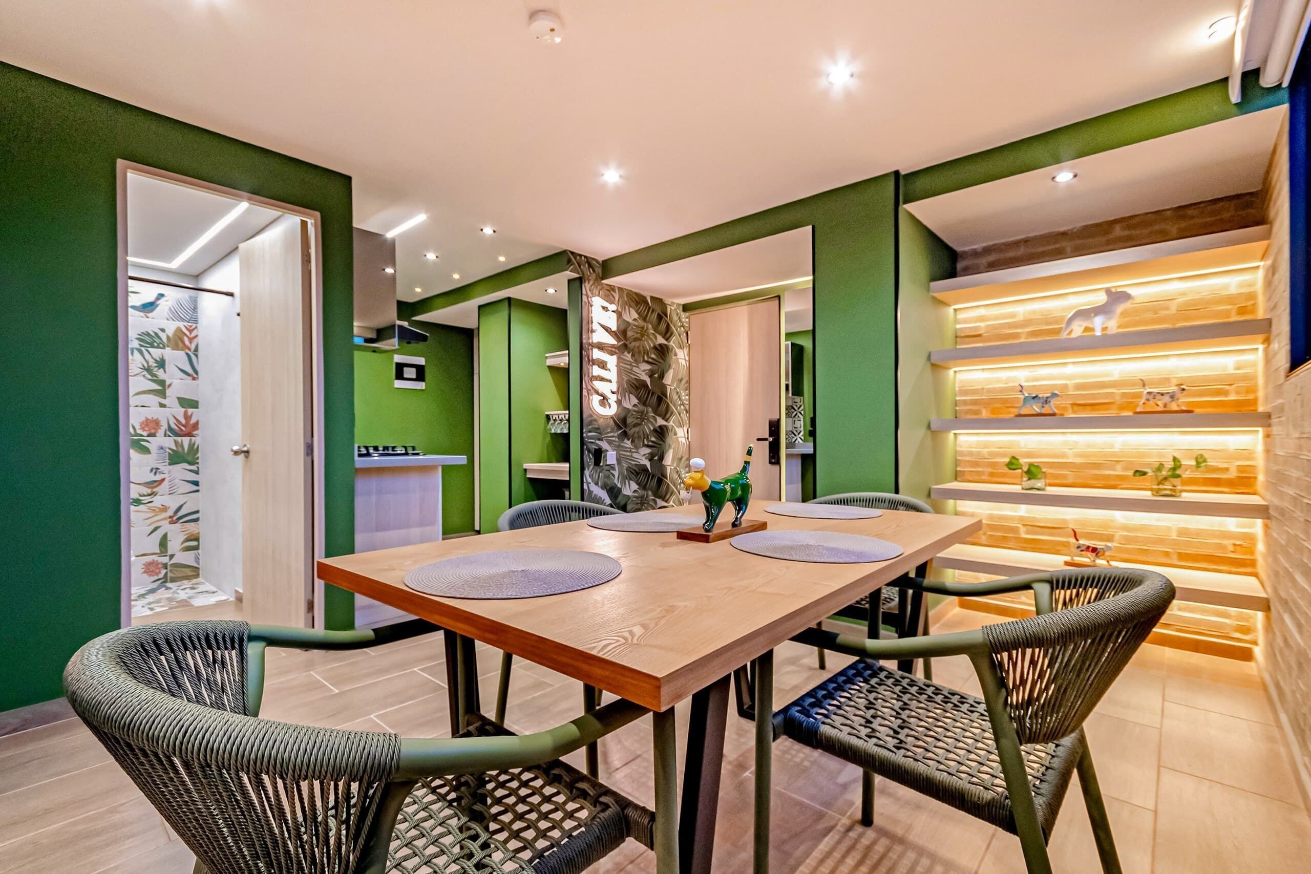 A dining area with a wooden table, four chairs, and a decorative wall with shelves.