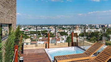 Une terrasse sur le toit, dotée d’un jacuzzi et de chaises longues, offrant une vue panoramique sur la ville.