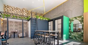 A modern office space with a loft area, a staircase, and a green accent wall. - Edificio Habitare Cristales (Cali)