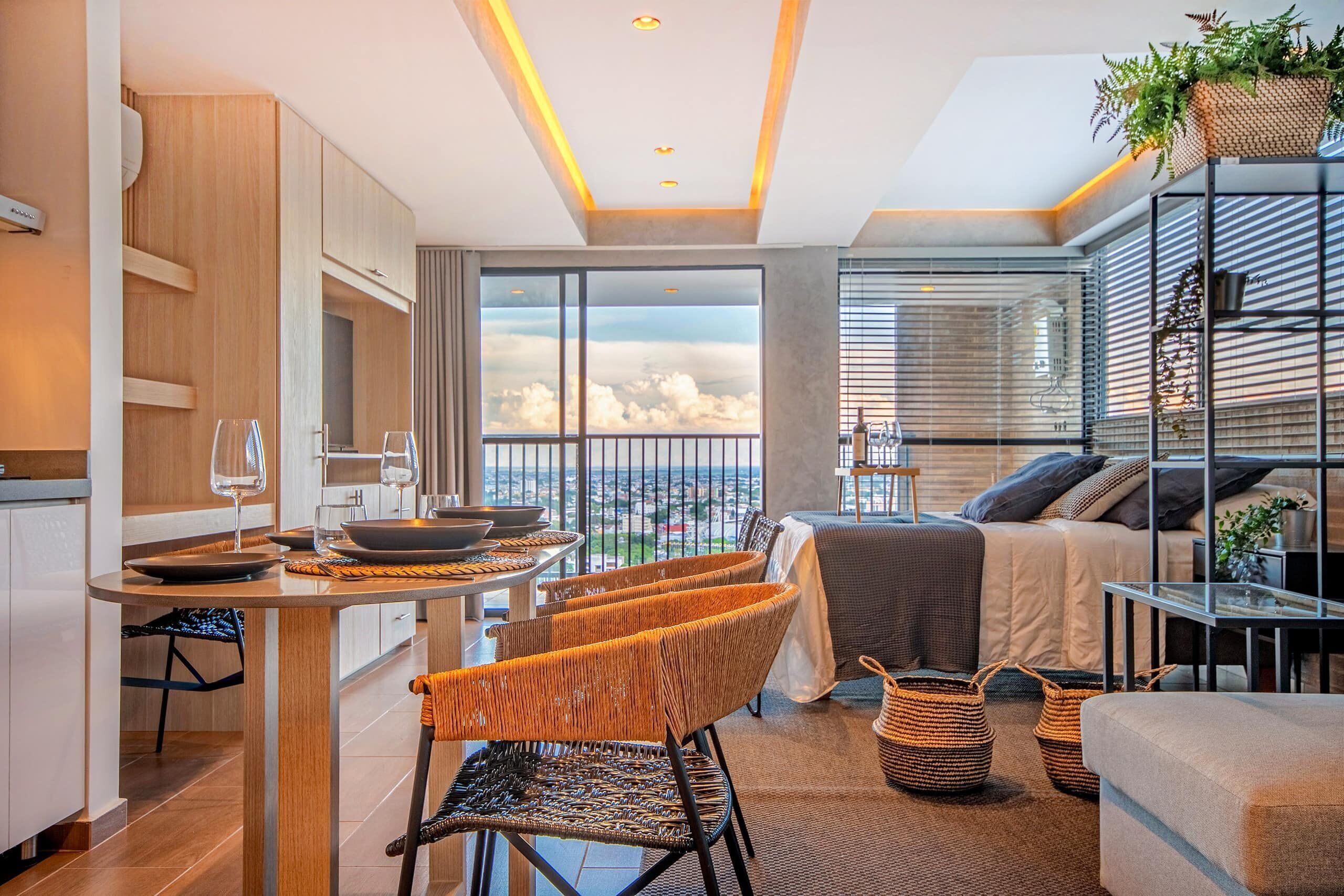 A modern apartment with a kitchen, dining area, and a balcony with a city view.