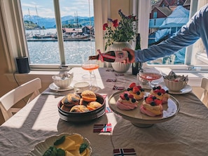 A table set with food, drinks, and a view of a harbor.