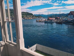 A harbor with boats, a white picket fence, and a mountainous backdrop.