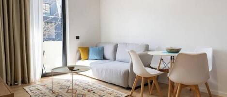 Una sala de estar moderna con un sofá, dos sillones, una mesita y una alfombra estampada.
