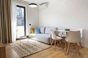 A modern living room with a sofa, two chairs, a small table, and a patterned rug. - Barrikada-E – Modern Central Apartments with Balcony in Tirana (Tiranë)