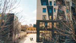 En modern byggnad med en geometrisk fasad, en parkeringsplats och en klar himmel.