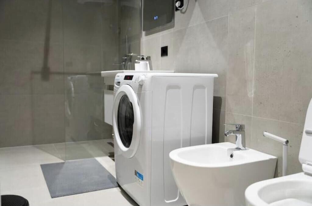 A modern bathroom with a washing machine, bidet, and sink.