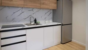 Eine Küche mit weißen Schränken, einer Marmor-Spritzschutzleiste, einem Edelstahl-Kühlschrank und einer Holzarbeitsplatte.