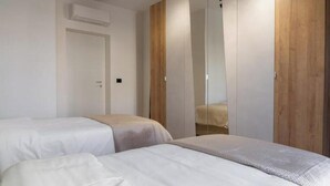 Ein Schlafzimmer mit zwei Betten, einem Holzschrank und einem Spiegel.
