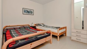 Quarto com duas camas de madeira, um guarda-roupa e um quadro emoldurado na parede.
