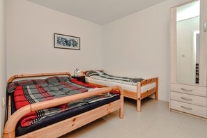 A bedroom with two wooden beds, a wardrobe, and a framed picture on the wall. - Apartment Bokan (Vir)