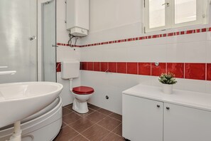 A bathroom with a white sink, red toilet, and white cabinets. - Apartment Bokan (Vir)