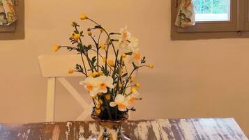 Een eettafel met een bloevas, een schilderij aan de muur en een raam met gordijnen.