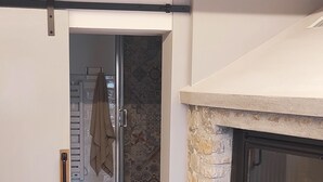 A room with a stone fireplace, a door leading to another room, and a patterned floor.