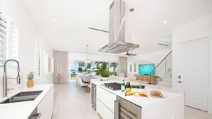 Et moderne køkken med en central ø, integreret hårde hvidevarer og et spiseområde med udsigt til det fri.