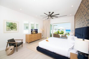 Ein Schlafzimmer mit einem Bett, einem Schreibtisch, einem Stuhl, einer Kommode und Blick auf das Meer.