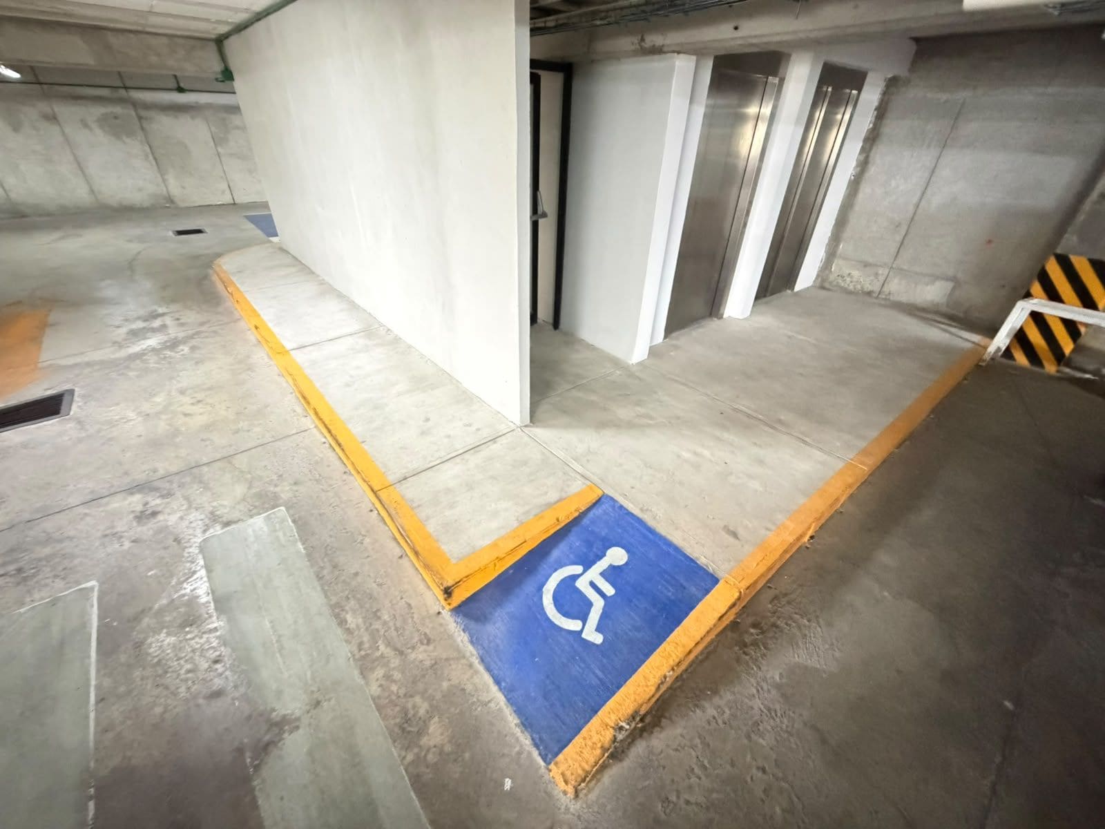 Un estacionamiento con un espacio reservado para discapacitados, señalizado con un letrero azul y el símbolo de una silla de ruedas blanca.