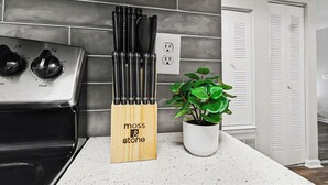 A kitchen with a stove, a knife block, and a potted plant. - Bright/Spacious 2BR - King Bed/Pool/Gym Near UAB/Hospitals (Homewood)