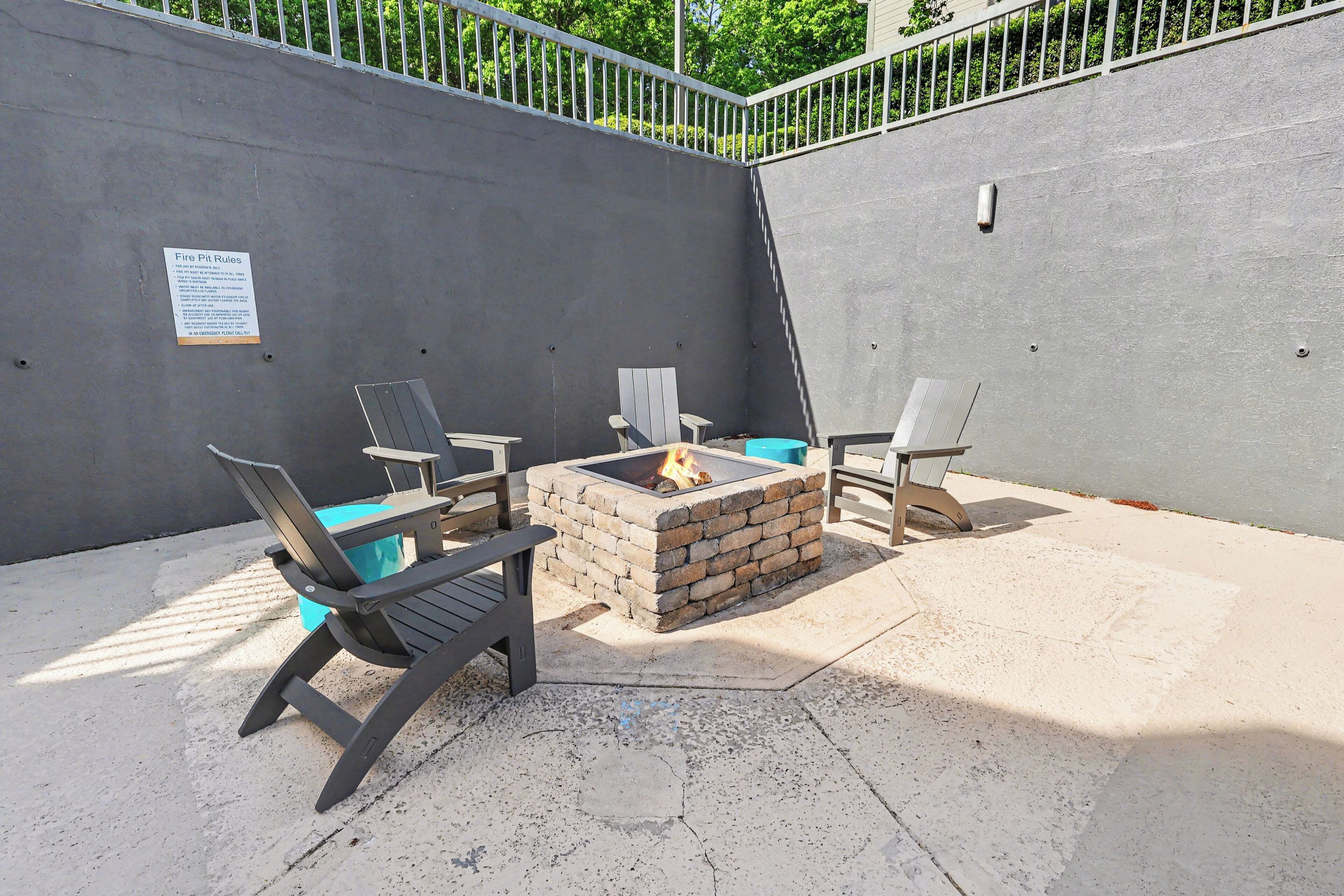 Eine Terrass mit Feuerstelle, zwei Adirondack-Stühlen und einem Betonboden.