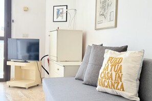 A room with a bed, a TV on a stand, a white cabinet, and a wall with framed pictures. - SE256 - Senigallia, one-bedroom apartment (Senigallia)