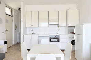 A compact kitchen with white cabinets, a built-in oven, and a washing machine. - SE256 - Senigallia, one-bedroom apartment (Senigallia)