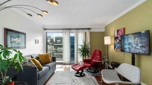 Un soggiorno moderno con divano, poltrone, televisore e un balcone.