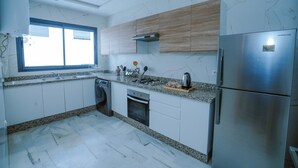 Una cocina moderna con un refrigerador de acero inoxidable, un horno empotrado y una ventana sobre el fregadero.