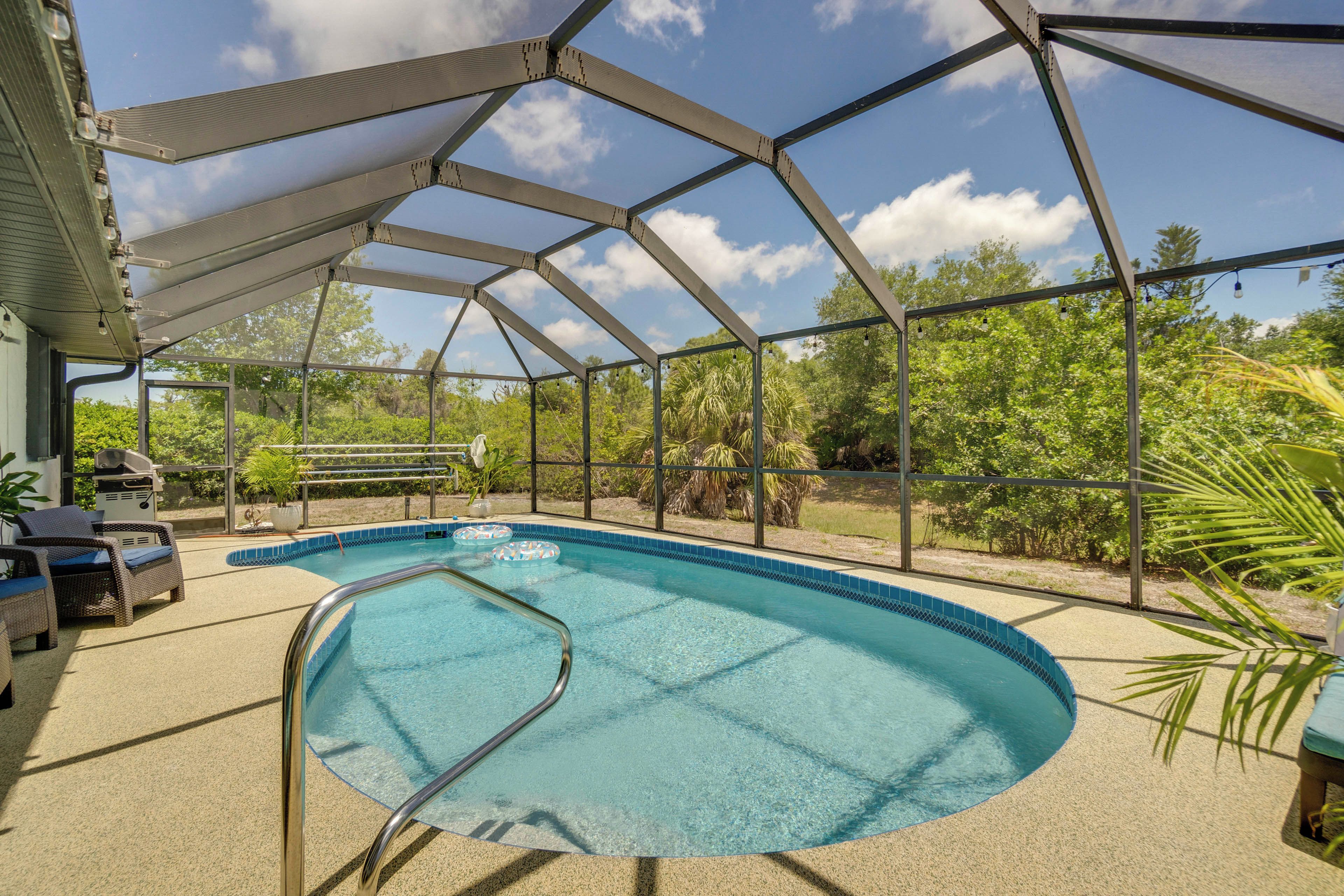 An outdoor swimming pool with a glass enclosure, surrounded by lounge chairs and a barbecue area.