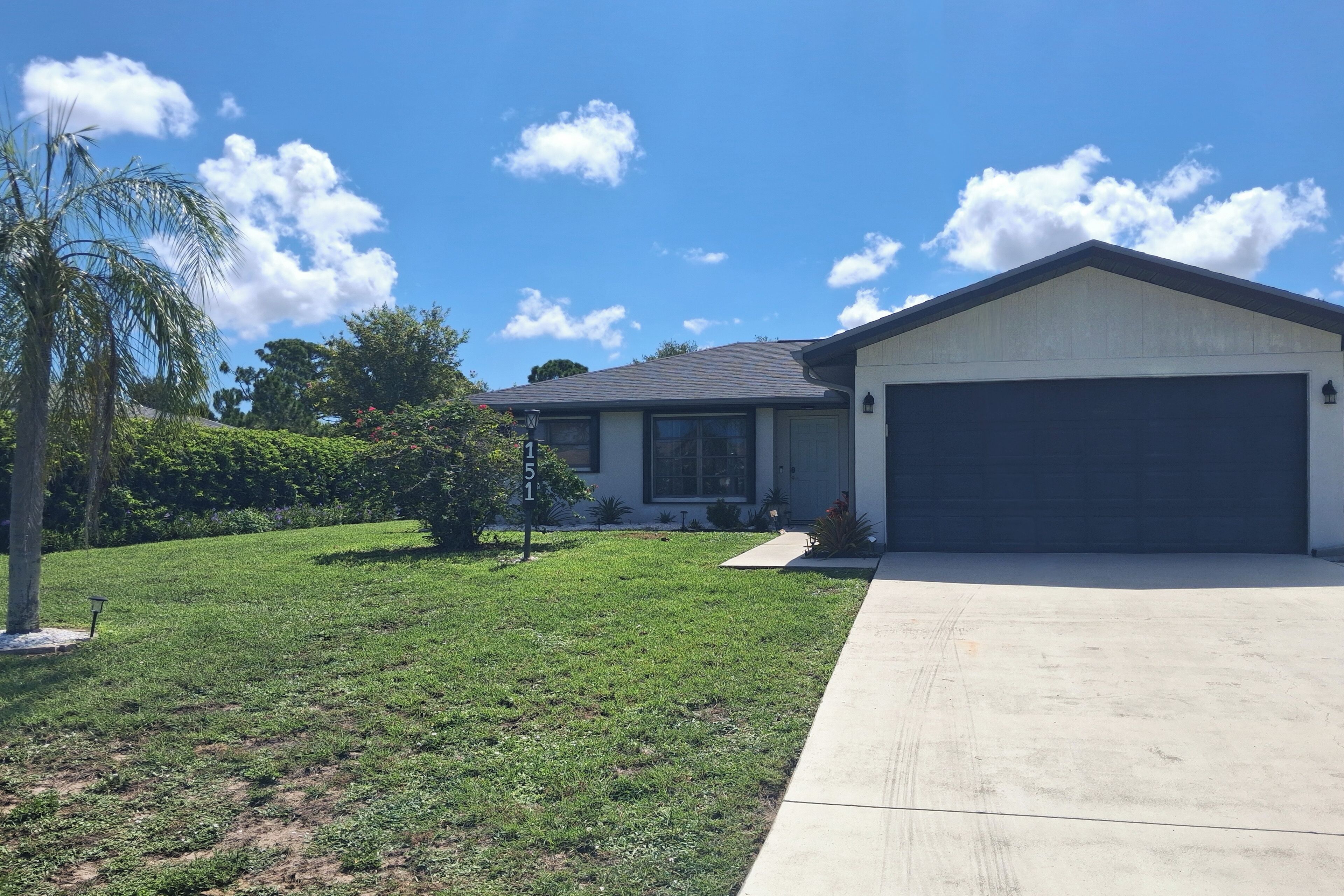 A residential house with a garage, a well-maintained lawn, and a clear sky.