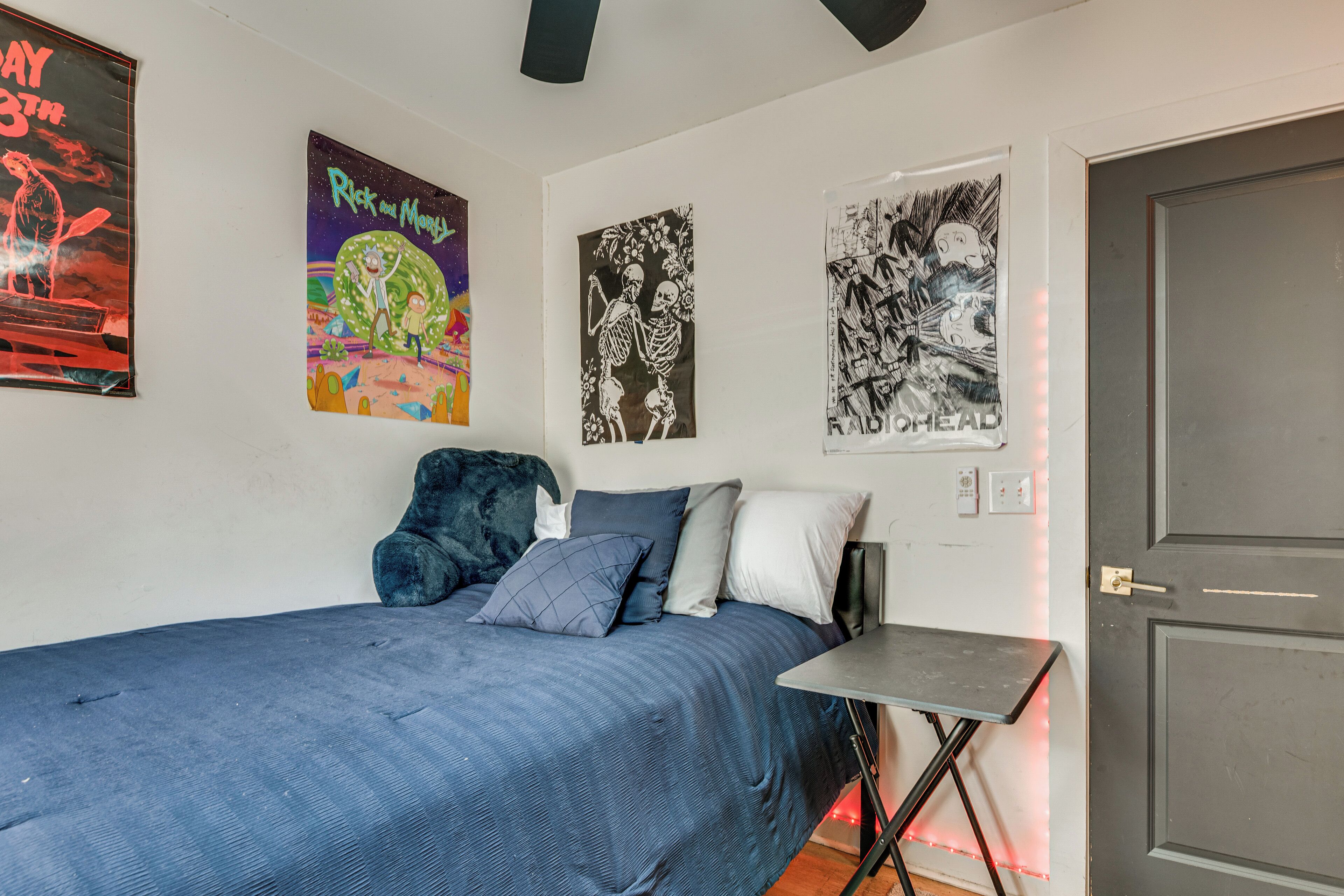 A bedroom with a bed, a small table, and wall art.