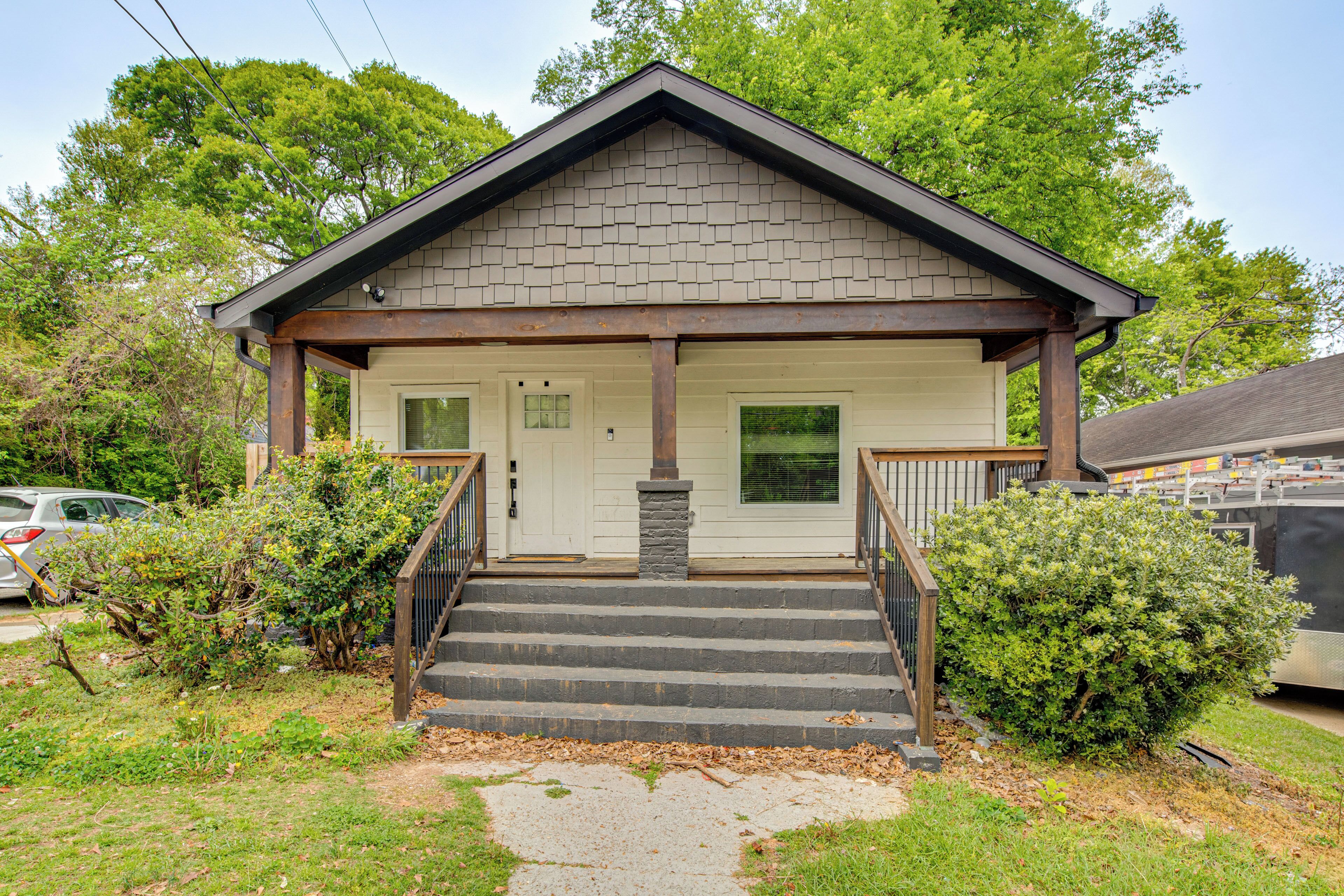 A two-story house with a front porch, a set of stairs leading to the entrance, and a garage in the background.